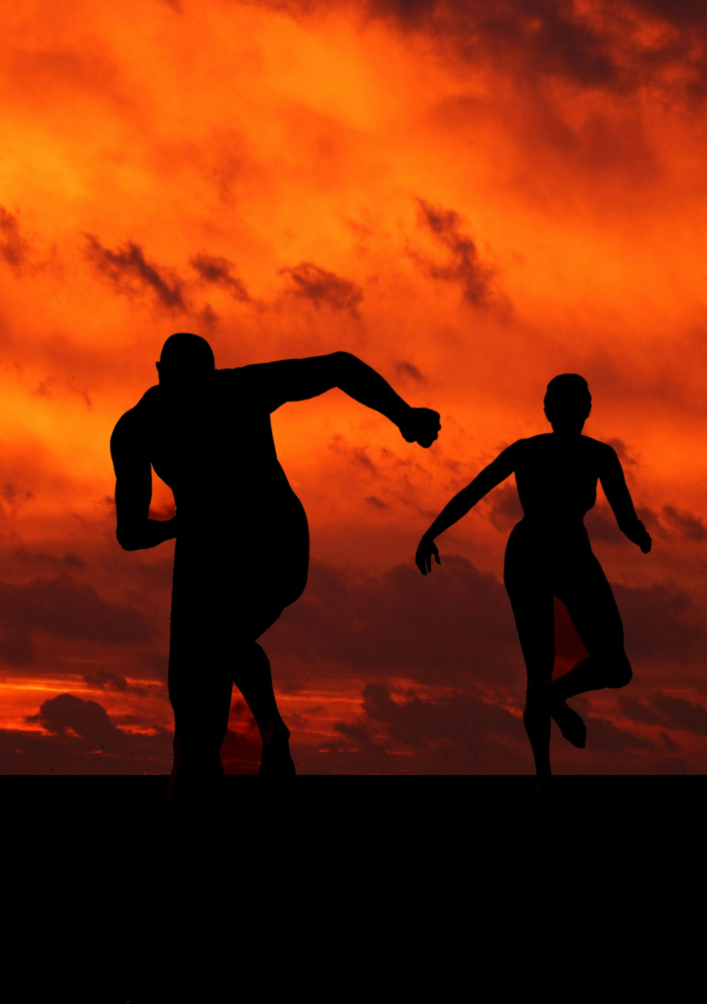Silhouette of runners at sunset with dramatic orange sky